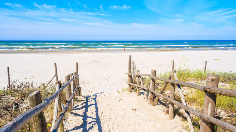 Blick durch den Aufgang zum Strand hin zum Meer, symbolisch für den Start in die Sommerferien