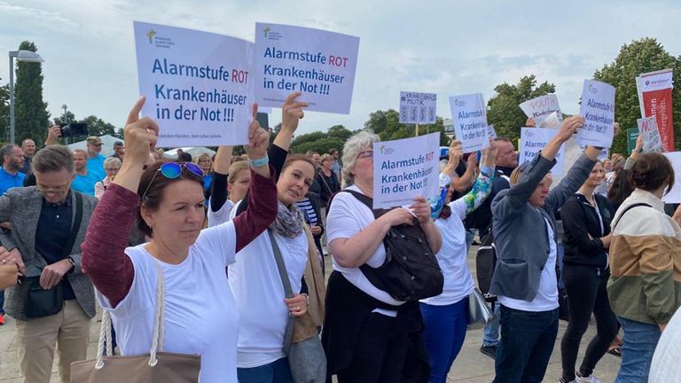 Mitarbeitende der Immanuel Klinik Rüdersdorf weisen mit Plakaten auf die Notlage der Krankenhäuser bei der Kundgebung hin